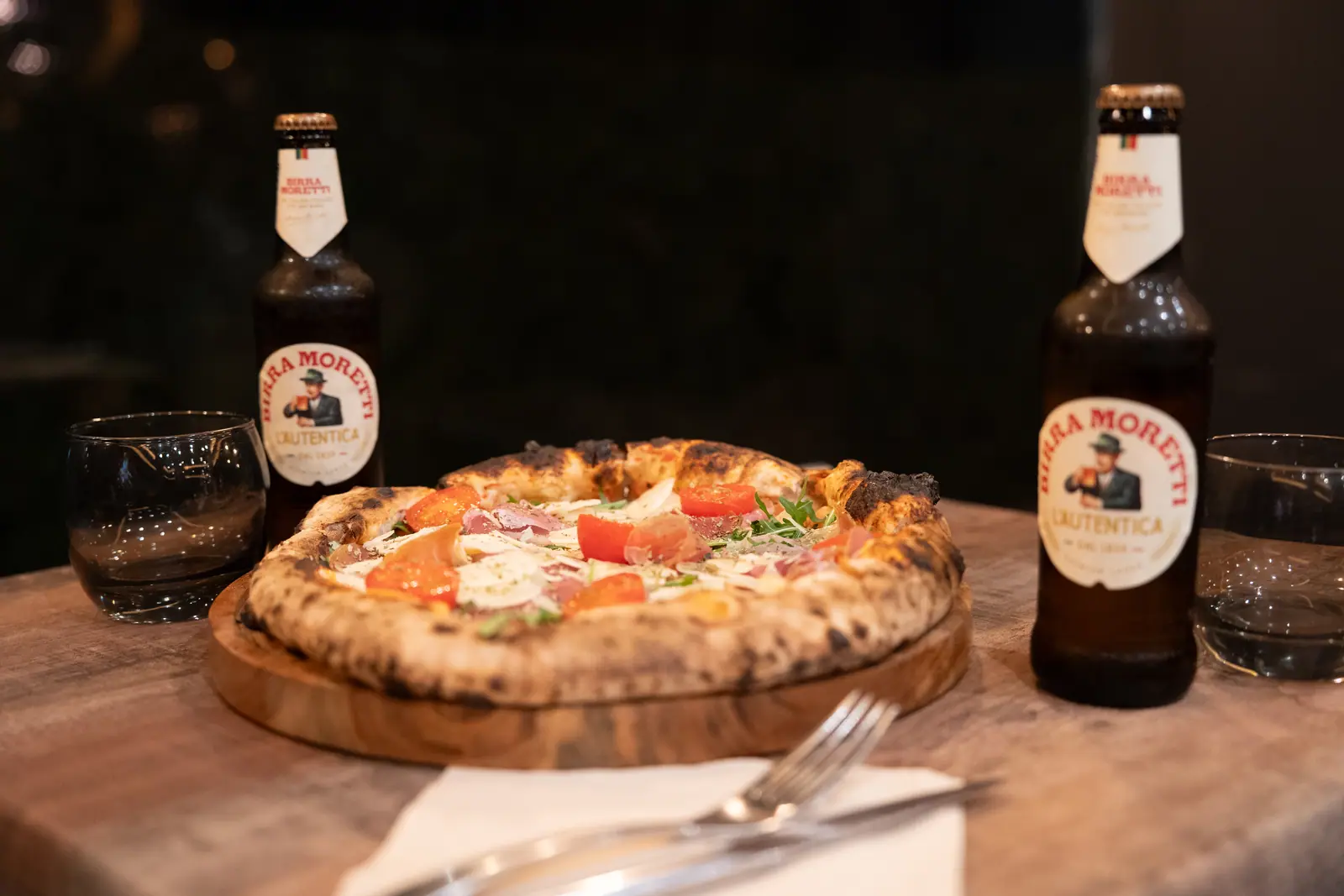 Une pizza servie avec deux bières italiennes