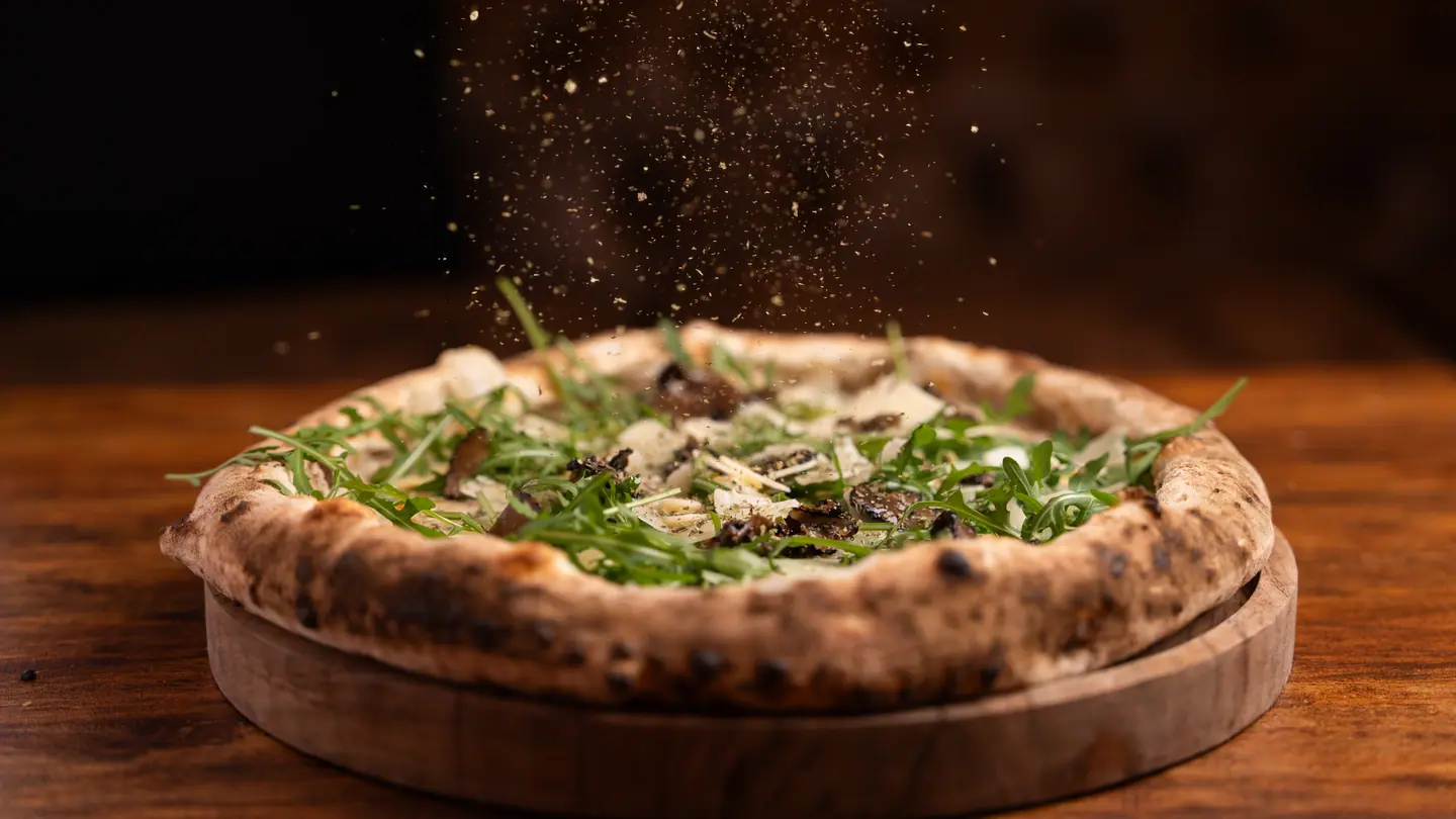 Una Tartufo sul suo tagliere, il tartufo cade a pioggia su rucola e parmigiano