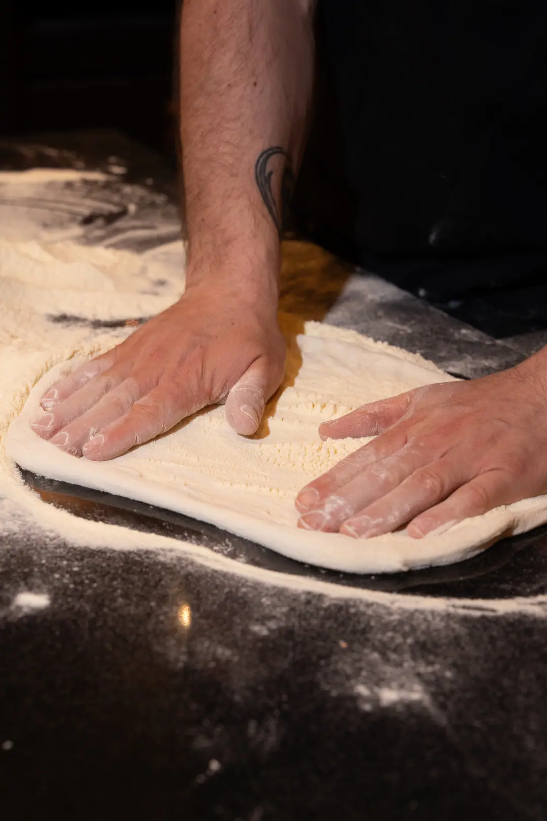 Une pâte étalée à la main sur le plan fariné